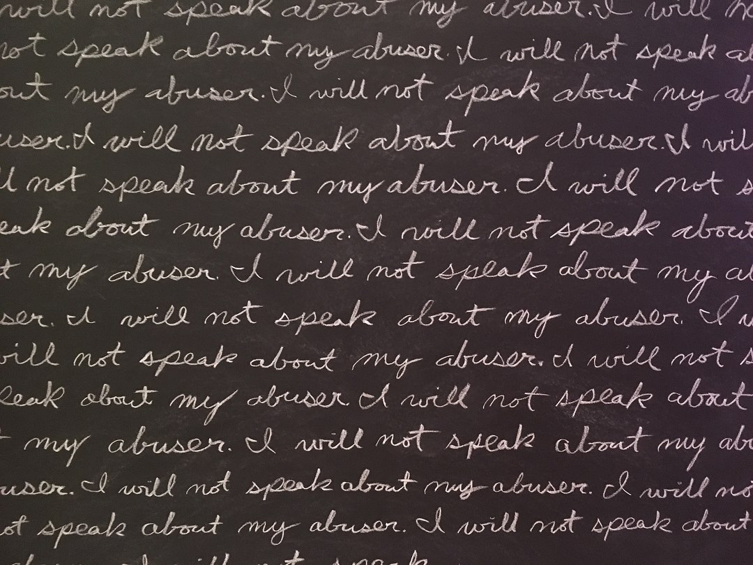 close up of chalkboard text "I will not speak about my abuser"